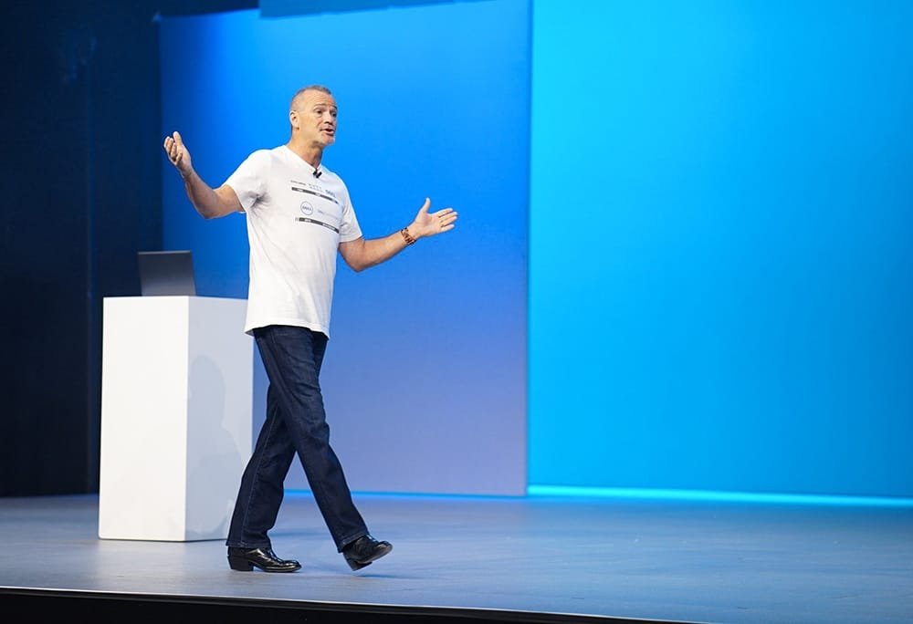 Jeff Clarke COO da Dell - Apresentação Windows 11 Jeff Clarke, COO da Dell, gesticulando no palco durante apresentação sobre o mercado de PCs e adoção do Windows.