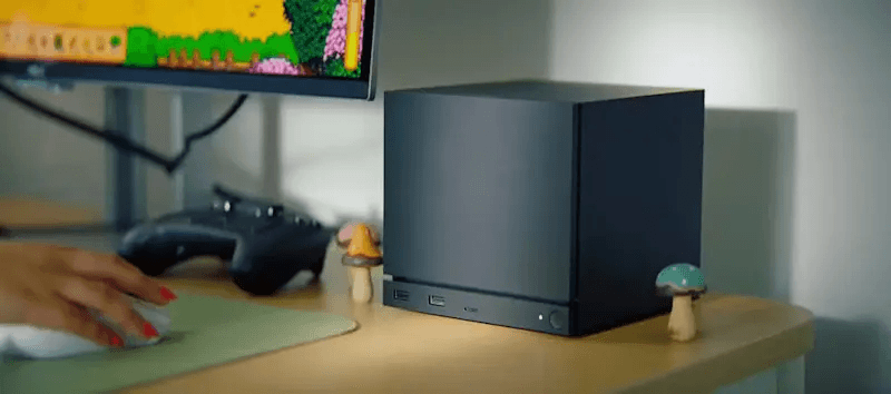 Steam Machine posicionada em uma mesa de escritório conectada a monitor e periféricos, funcionando como PC.